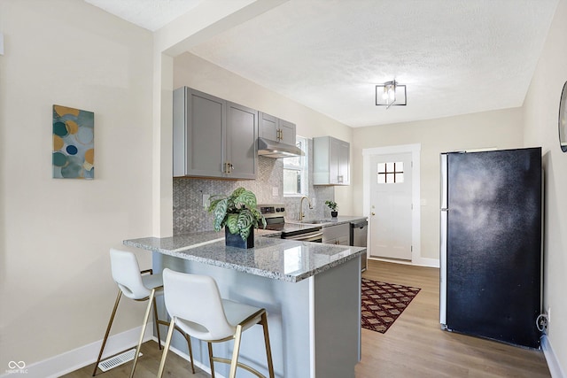 kitchen with stainless steel appliances, gray cabinetry, and kitchen peninsula