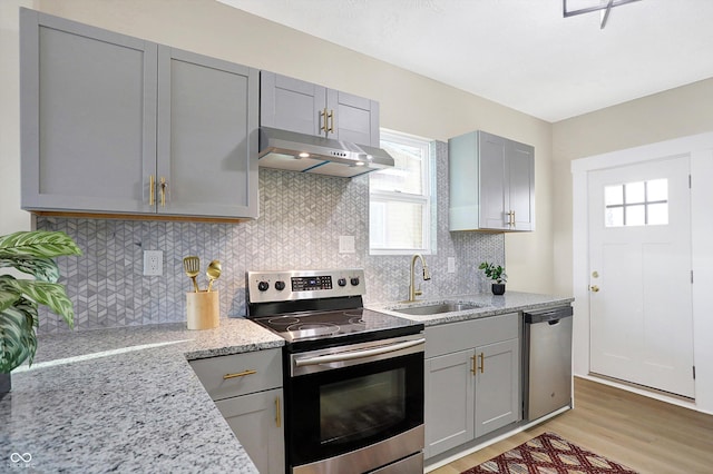 kitchen with light stone counters, sink, gray cabinets, and appliances with stainless steel finishes