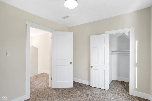 unfurnished bedroom with light colored carpet and a closet