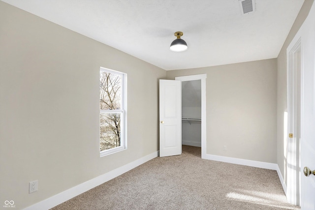 unfurnished bedroom featuring a spacious closet, a closet, and carpet