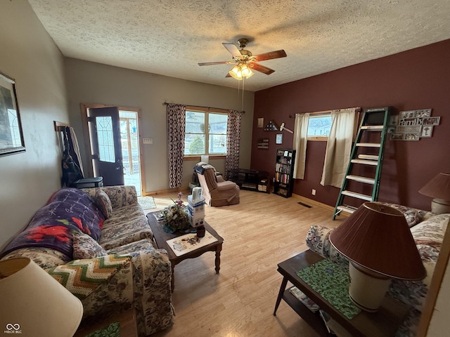 living room featuring vaulted ceiling, a textured ceiling, ceiling fan, and light hardwood / wood-style floors