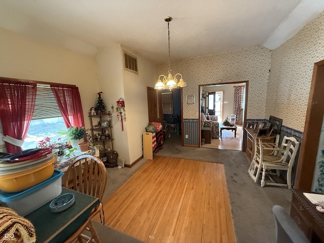 carpeted dining space featuring lofted ceiling, a wealth of natural light, and a chandelier