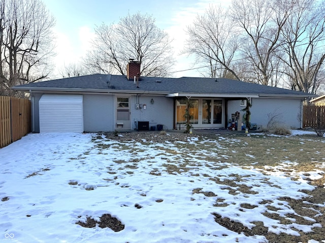 snow covered rear of property featuring a garage and central AC