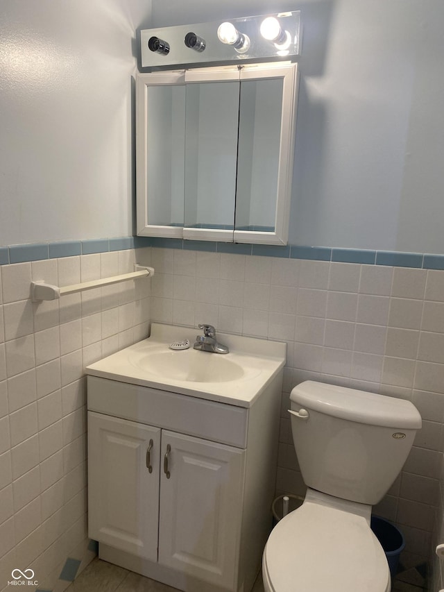 bathroom with tile patterned flooring, vanity, tile walls, and toilet