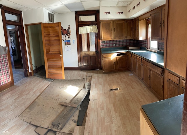 kitchen featuring a paneled ceiling, decorative backsplash, and light hardwood / wood-style flooring