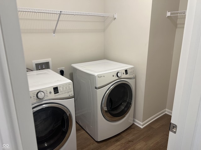 clothes washing area with washing machine and clothes dryer and dark hardwood / wood-style flooring