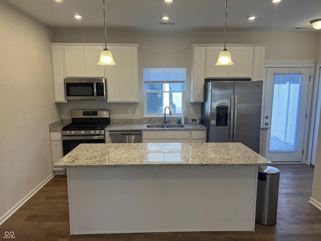 kitchen with pendant lighting, appliances with stainless steel finishes, sink, and a kitchen island