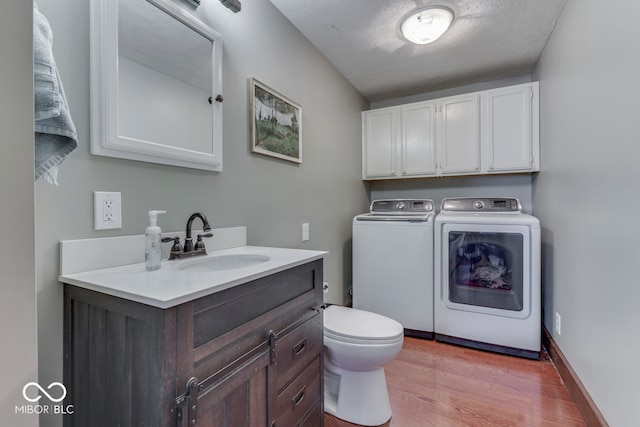 washroom featuring washer and dryer, sink, a textured ceiling, and light wood-type flooring