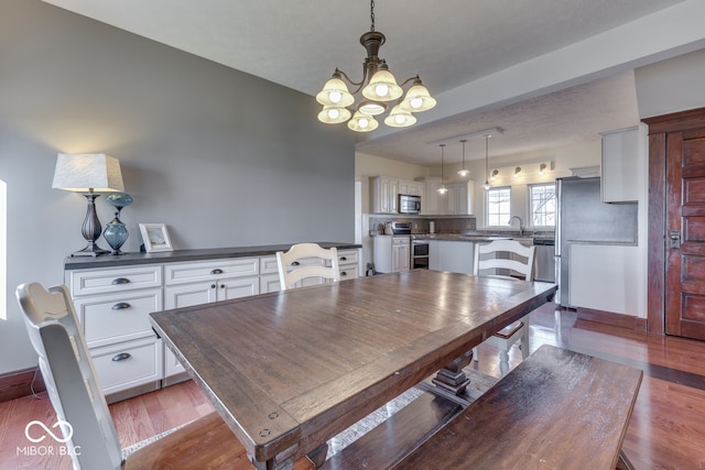 dining space featuring sink, dark wood-type flooring, and a chandelier