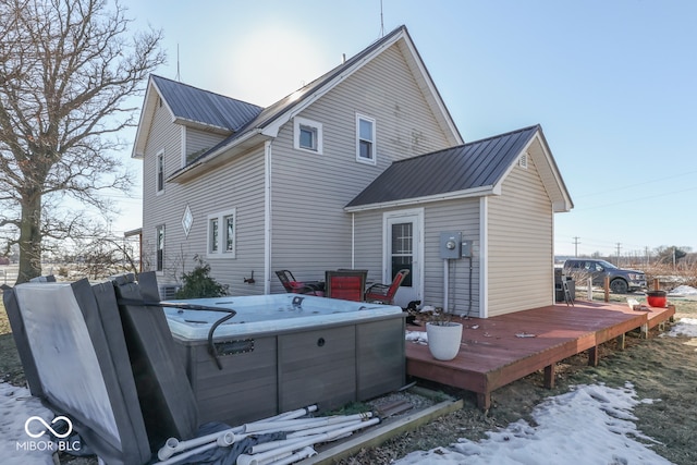 snow covered property with a hot tub and a deck