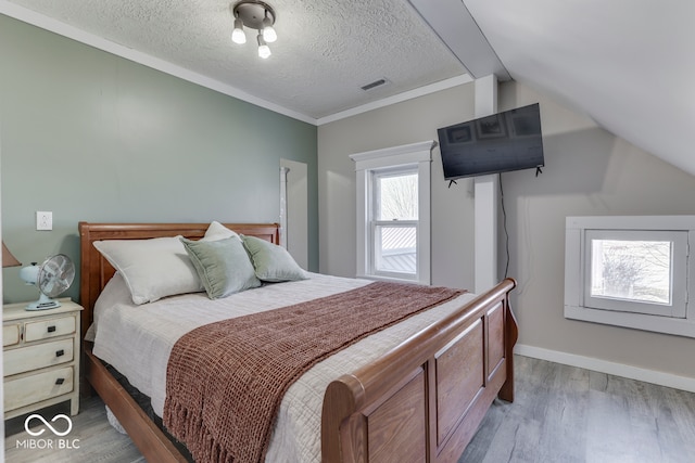 bedroom featuring crown molding, lofted ceiling, a textured ceiling, and light hardwood / wood-style floors