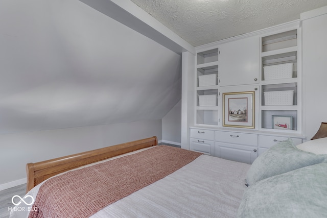 bedroom with vaulted ceiling and a textured ceiling