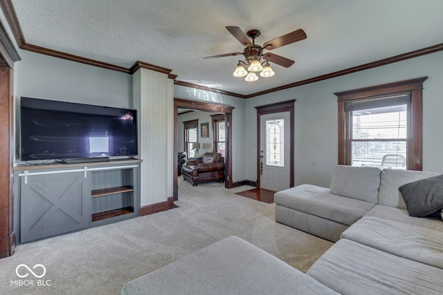 living room featuring ornamental molding, light colored carpet, ceiling fan, and a textured ceiling