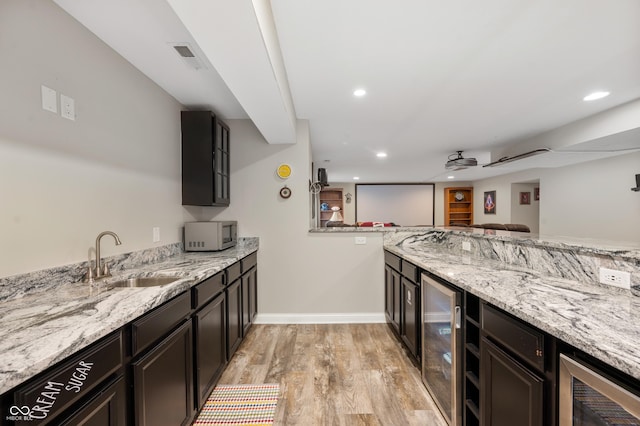 kitchen featuring sink, light stone counters, wine cooler, and light wood-type flooring