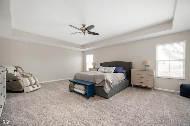 bedroom with a raised ceiling, carpet floors, and ceiling fan