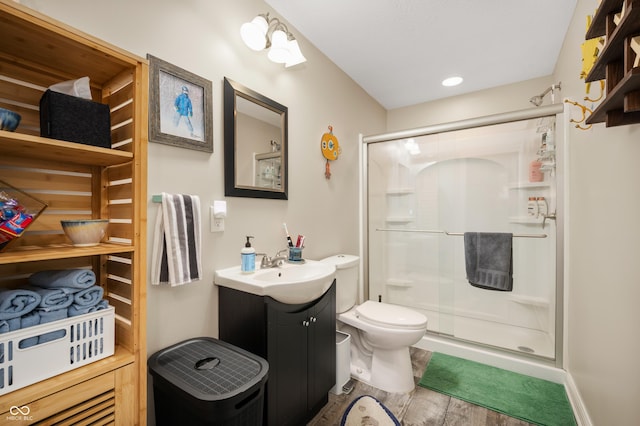 bathroom with a shower with door, vanity, hardwood / wood-style flooring, and toilet