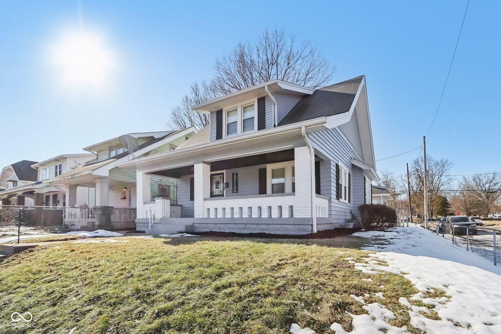 bungalow with covered porch and a front lawn