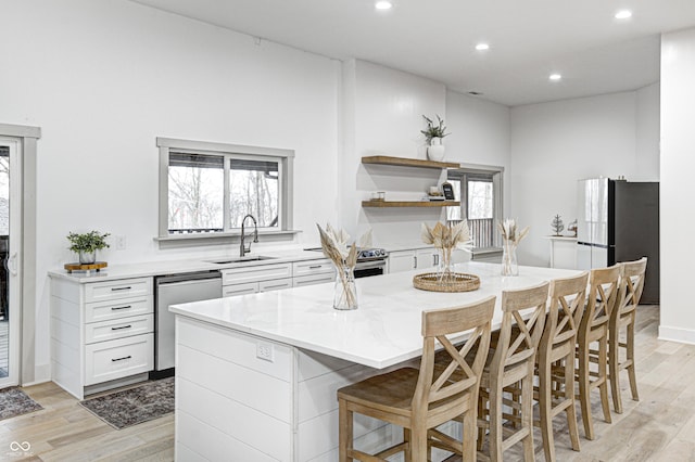 kitchen with sink, a breakfast bar area, stainless steel appliances, a center island, and white cabinets