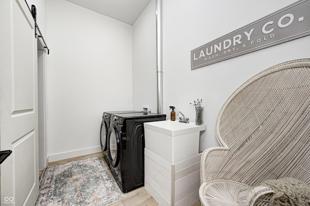 laundry room with a barn door, light hardwood / wood-style floors, and washer and dryer