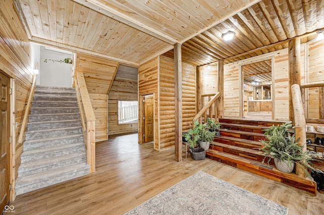 stairs with log walls, hardwood / wood-style floors, and wooden ceiling