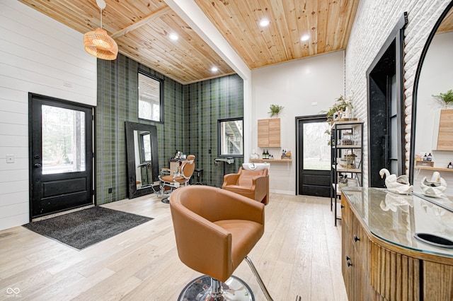 interior space with light hardwood / wood-style flooring, wooden ceiling, and a high ceiling