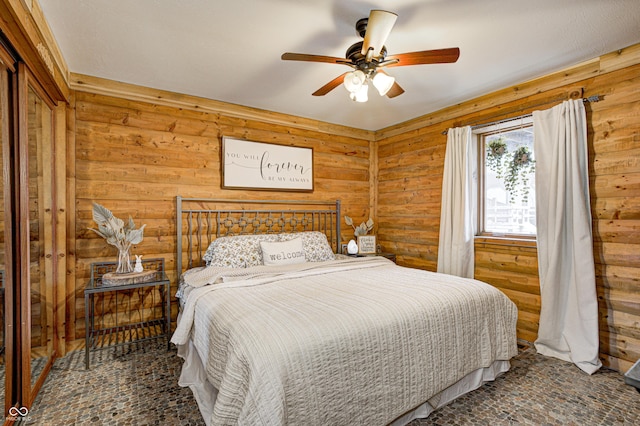 bedroom featuring ceiling fan and wood walls