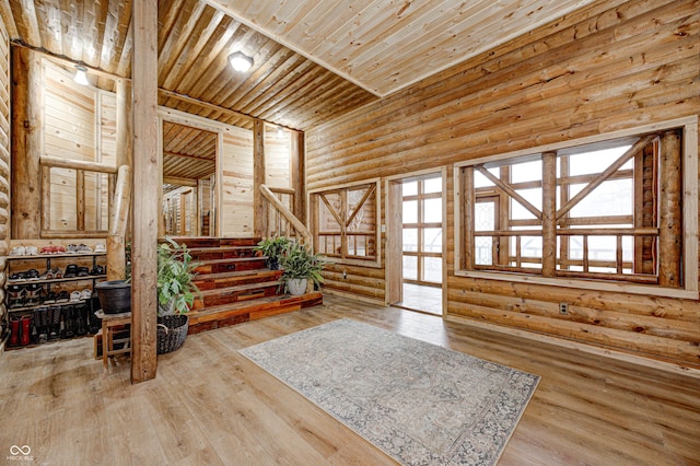 foyer entrance featuring hardwood / wood-style flooring, a wealth of natural light, wooden ceiling, and log walls