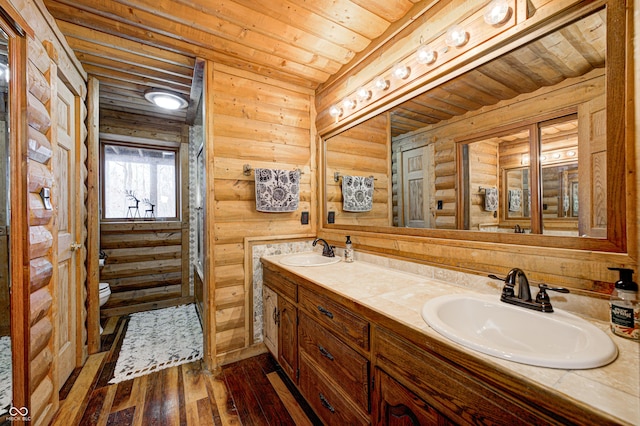 bathroom featuring wood ceiling, hardwood / wood-style floors, vanity, log walls, and toilet