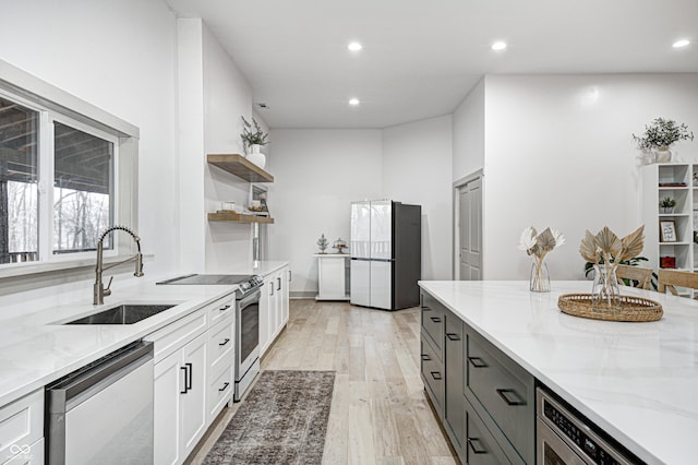 kitchen featuring white cabinetry, sink, stainless steel appliances, and light stone countertops