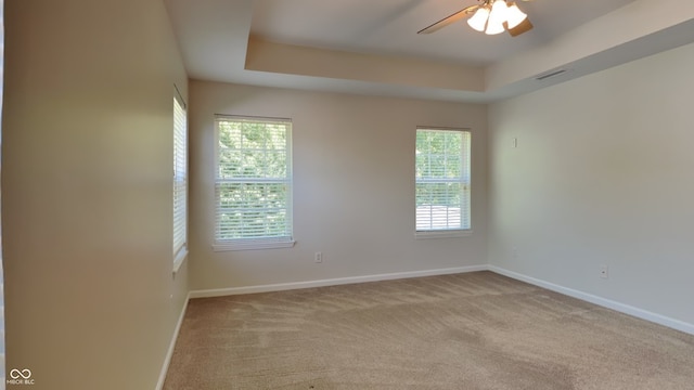 carpeted empty room with ceiling fan and a raised ceiling