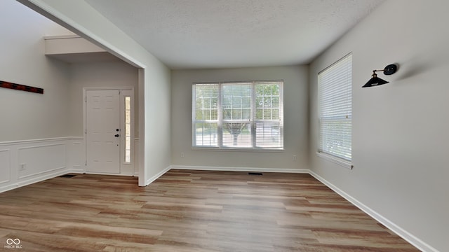 foyer entrance featuring a textured ceiling and light hardwood / wood-style flooring