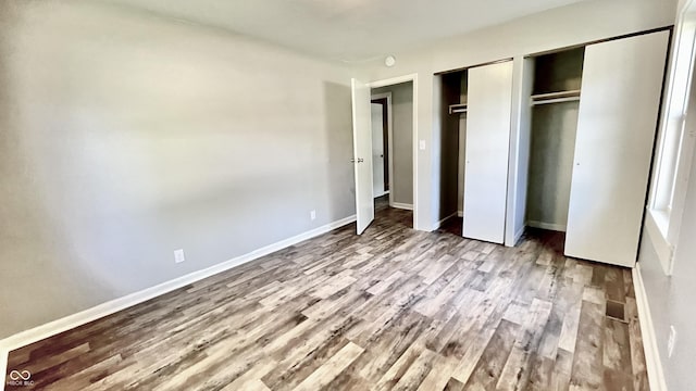 unfurnished bedroom with two closets and light wood-type flooring