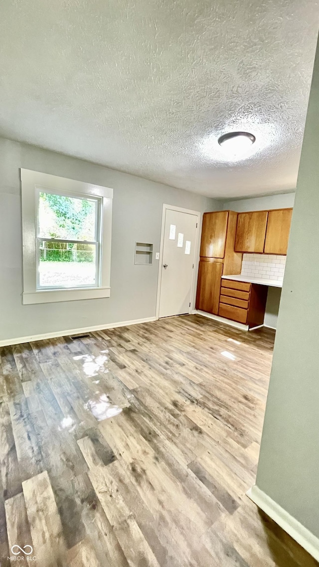 unfurnished living room featuring a textured ceiling and light wood-type flooring