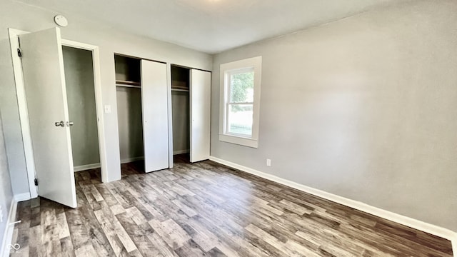 unfurnished bedroom with multiple closets and wood-type flooring