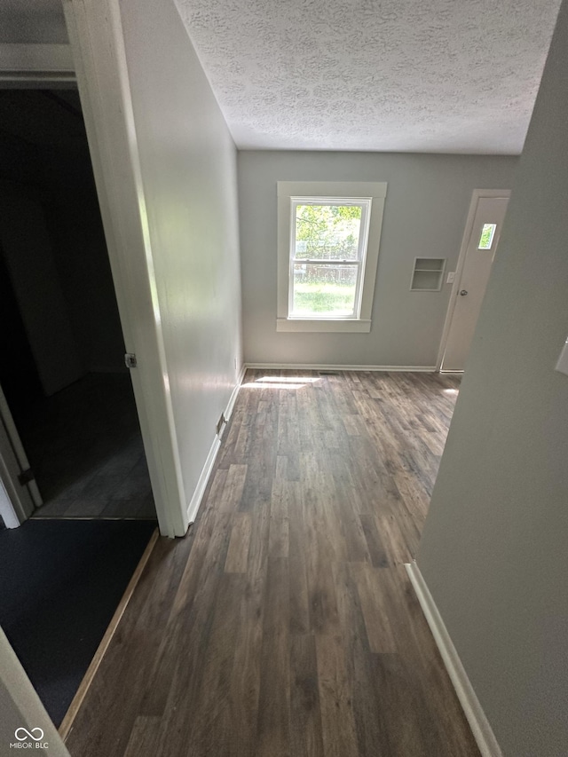 corridor featuring dark hardwood / wood-style flooring and a textured ceiling