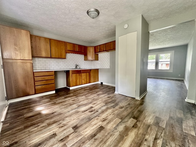 kitchen featuring dark hardwood / wood-style flooring, backsplash, and sink