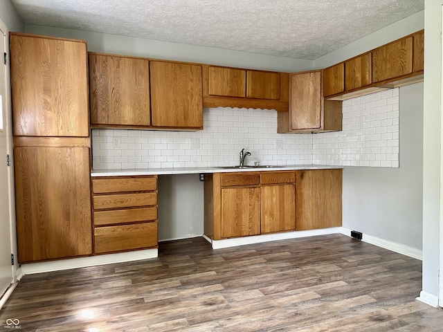 kitchen with dark hardwood / wood-style flooring, sink, backsplash, and a textured ceiling