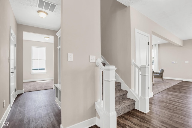 stairs featuring wood-type flooring and a textured ceiling