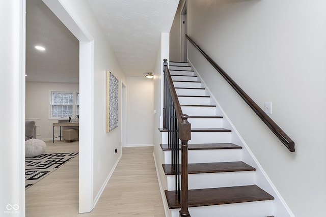 stairway with wood-type flooring and a textured ceiling