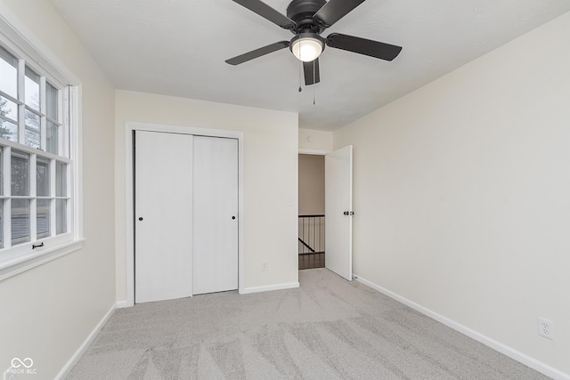 unfurnished bedroom featuring light carpet, a closet, and ceiling fan