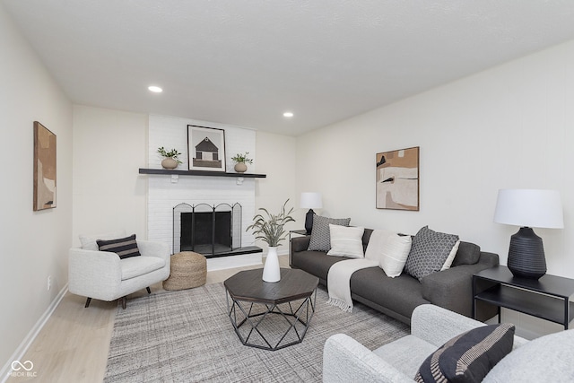 living room featuring a brick fireplace and light hardwood / wood-style flooring