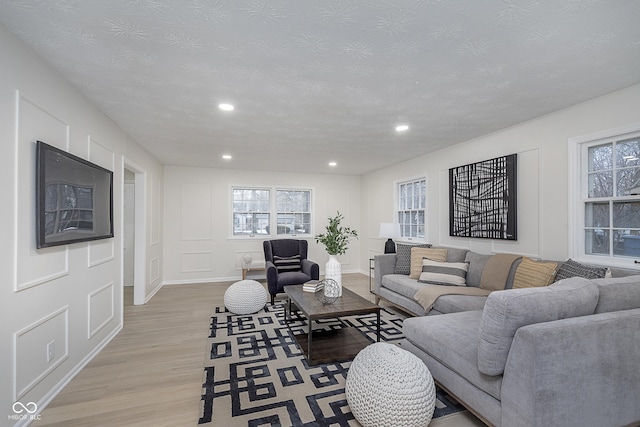 living room with plenty of natural light, a textured ceiling, and light wood-type flooring