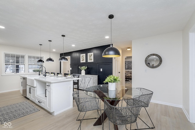 dining area featuring sink, a textured ceiling, and light hardwood / wood-style flooring