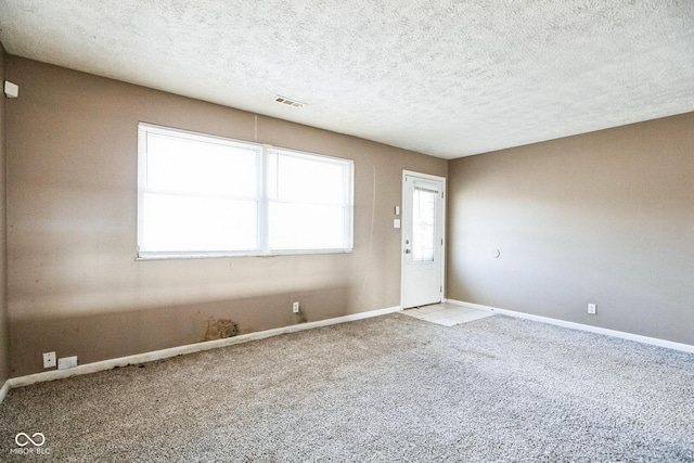 carpeted empty room with a textured ceiling