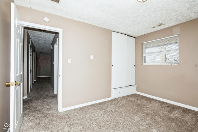 unfurnished bedroom with a closet, carpet, and a textured ceiling