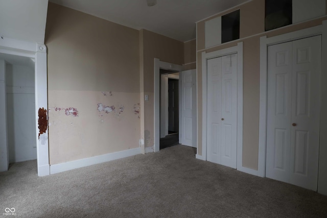 unfurnished bedroom with two closets and carpet flooring