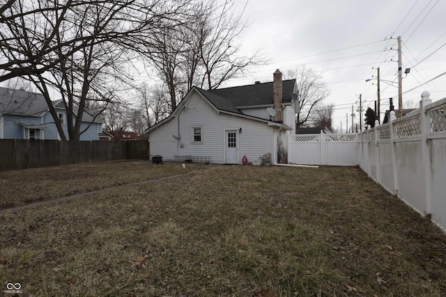 view of property exterior featuring a fenced backyard, a lawn, and a chimney