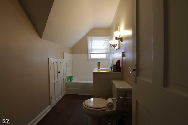 bathroom featuring toilet, a garden tub, lofted ceiling, wood finished floors, and a sink