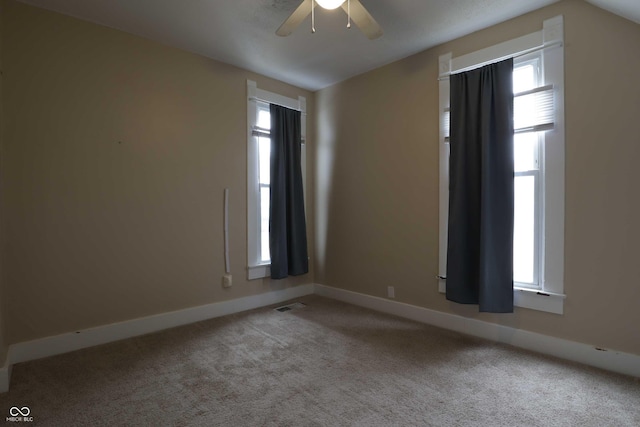 carpeted empty room with visible vents, baseboards, and ceiling fan