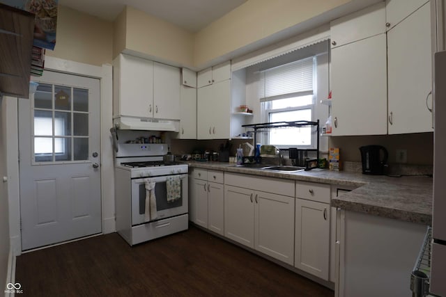 kitchen featuring white range with gas cooktop, dark wood-style flooring, a sink, under cabinet range hood, and white cabinetry